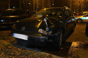 Na zdjęciu widać uszkodzony zaparkowany ciemny pojazd.
