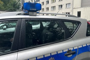 Na zdjęciu widać bok policyjnego radiowozu a w tle żorską komendę Policji.