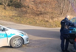 Na zdjęciu widać policjanta, kontrolowany samochód i dwa radiowozy.