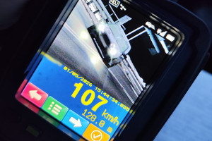 Na zdjęciu widać wskazania miernika prędkości oraz samochód na drodze.