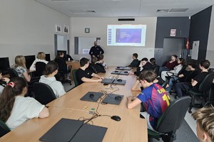 Na zdjęciu widać policjanta oraz uczniów w sali lekcyjnej.