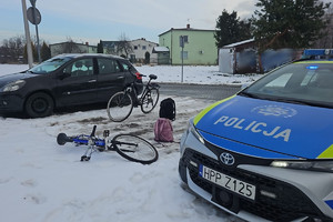 Na zdjęciu widać radiowóz, dwa rowery oraz zaparkowany obok ciemny pojazd. Drogi są zaśnieżone.