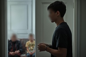 Na grafice widać nastolatka z założonymi kajdankami na rękach, a w tle mieszkania widać dwie osoby.