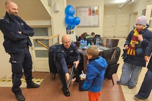 Na zdjęciu widać policjantów oraz dzieci przed stanowiskiem promocyjnym.