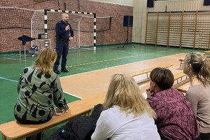 Na zdjęciu widać policjanta i rodziców podczas spotkania w sali gimnastycznej szkoły.
