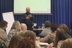 Na zdjęciu widać policjanta oraz nauczycieli podczas spotkania.