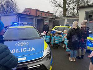 Na zdjęciu widać radiowóz, policjantów oraz przedszkolaków wraz z ich opiekunkami.