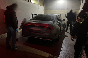 Na zdjęciu widać policjantów, szary samochód oraz zatrzymane osoby.