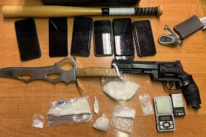 Na zdjęciu widać zabezpieczone przez policjantów przedmioty, w tym woreczki z zawartością białej substancji, nóż i kij baseballowy.