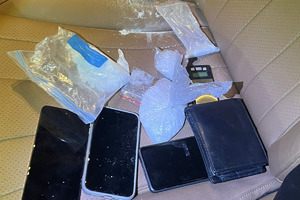 Na zdjęciu widać przedmioty pozostawione na siedzeniu, w tym telefony i woreczki z białą substancją.