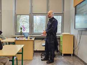 Na zdjęciu widać policjanta i uczniów w sali lekcyjnej.
