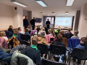 Na zdjęciu widać policjantów, zuchów i ich opiekunów podczas zwiedzania żorskiej komendy Policji.