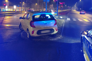 Na miejscy widać radiowóz, uszkodzony biały samochód i miejsce zdarzenia drogowego.