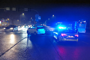 Na miejscy widać radiowóz, uszkodzony biały samochód i miejsce zdarzenia drogowego.