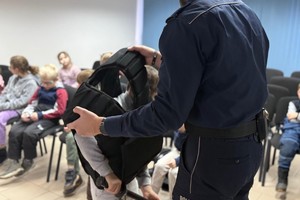 Na zdjęciu widać policjanta oraz przedszkolaki w trakcie profilaktycznych zajęć.