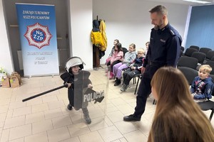 Na zdjęciu widać policjanta oraz przedszkolaki w trakcie profilaktycznych zajęć.