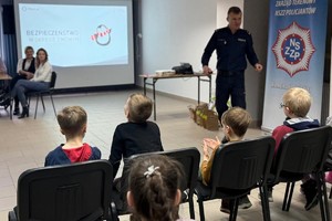 Na zdjęciu widać policjanta oraz przedszkolaki w trakcie profilaktycznych zajęć.
