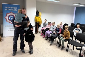 Na zdjęciu widać policjanta oraz przedszkolaki w trakcie profilaktycznych zajęć.
