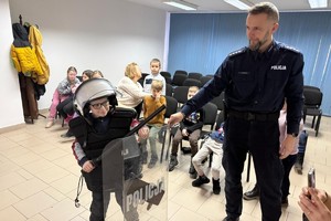 Na zdjęciu widać policjanta oraz przedszkolaki w trakcie profilaktycznych zajęć.