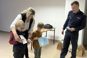 Na zdjęciu widać policjanta oraz przedszkolaki w trakcie profilaktycznych zajęć.
