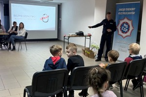 Na zdjęciu widać policjanta oraz przedszkolaki w trakcie profilaktycznych zajęć.