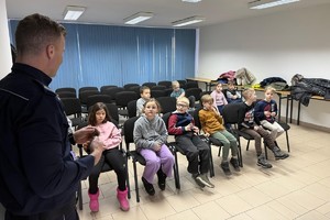 Na zdjęciu widać policjanta oraz przedszkolaki w trakcie profilaktycznych zajęć.