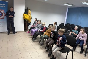 Na zdjęciu widać policjanta oraz przedszkolaki w trakcie profilaktycznych zajęć.