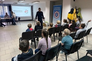 Na zdjęciu widać policjanta oraz przedszkolaki w trakcie profilaktycznych zajęć.