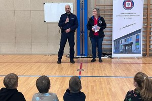 Na zdjęciu widać policjanta, przedstawicielkę sanepidu oraz zgromadzone dzieci.