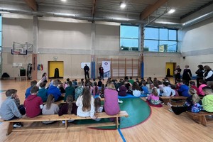 Na zdjęciu widać policjanta, przedstawicielkę sanepidu oraz zgromadzone dzieci.