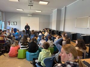 Na zdjęciu widać policjanta oraz uczniów zgromadzonych w klasie.