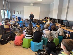 Na zdjęciu widać policjanta oraz uczniów zgromadzonych w klasie.