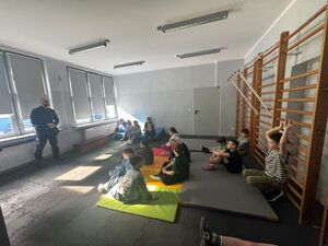 Na zdjęciu widać policjanta oraz uczniów zgromadzonych w klasie.