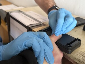 Na zdjęciu widać jak policjant pobiera od zatrzymanego odciski linii papilarnych.