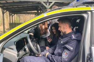Na zdjęciu widać policjantów i uczniów w trakcie wspólnych zajęć profilaktycznych w terenie.