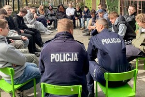 Na zdjęciu widać policjantów i uczniów w trakcie wspólnych zajęć profilaktycznych w terenie.