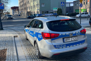Na zdjęciu widać policyjny radiowóz, rondo, park i budynek biblioteki.