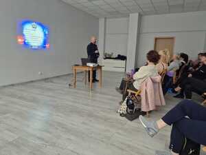Na zdjęciu widać policjanta i uczestników spotkania.