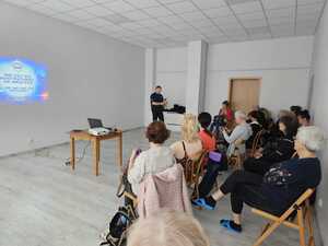 Na zdjęciu widać policjanta i uczestników spotkania.