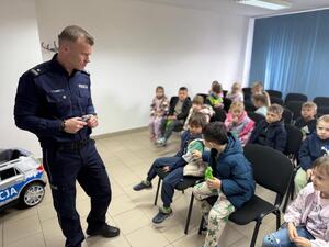 Na zdjęciu widać policjanta oraz przedszkolaki.