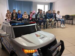 Na zdjęciu widać policjanta oraz przedszkolaki.