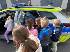 Na zdjęciu widać policjanta oraz przedszkolaki.