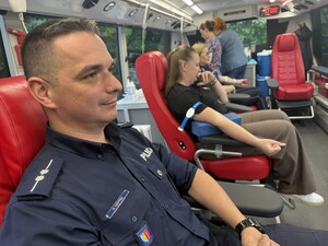 Na zdjęciu widać policjanta oraz inne osoby podczas akcji krwiodawstwa.