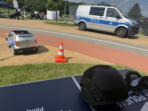 Na zdjęciu widać policjanta, radiowóz oraz uczestników biegu.
