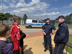 Na zdjęciu widać policjantów, radiowóz oraz uczestników biegu.