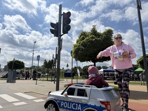 Na zdjęciu widać dziecko w samochodziku akumulatorowym i kobietę obok.