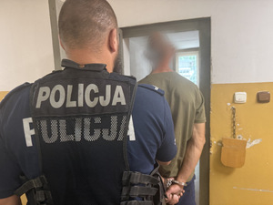 Na zdjęciu widać policjanta i zatrzymanego mężczyznę przed celą.