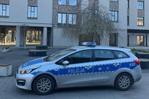 Na zdjęciu widać policyjny radiowóz a w tle budynki.