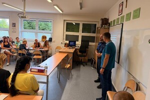 Na zdjęciu widać policjanta w sali oraz zgromadzone osoby podczas konferencji.