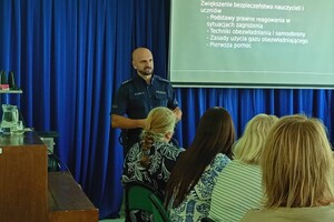 Na zdjęciu widać policjanta w sali oraz zgromadzone osoby podczas konferencji.